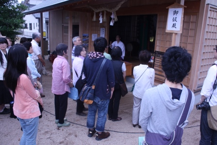 錦田剛志宮司から万九千神社の由来などを聴く様子