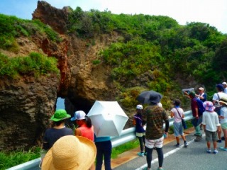 海蝕洞窟「弁慶の潮汲み穴」の地質学的説明を聞いている様子