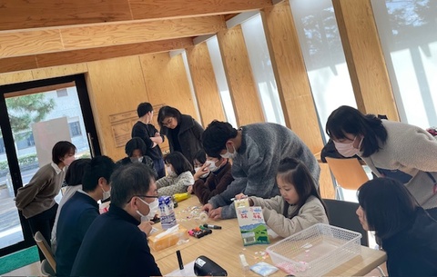 学生たちと一緒に牛乳パックで作った家を一生懸命つくり直す子どもたち