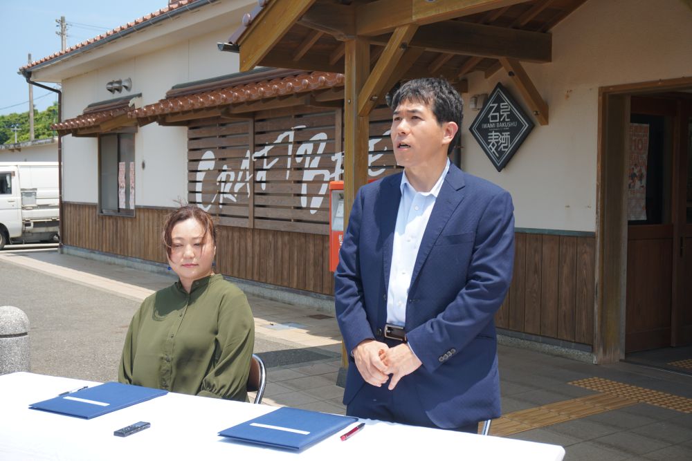 波子駅構内の桜の木から果実を採取する児玉特任教授（左）と  石見麦酒工場長の山口厳雄さん（右）